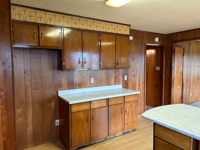 kitchen featuring wooden walls, ornamental molding, and light wood-type flooring