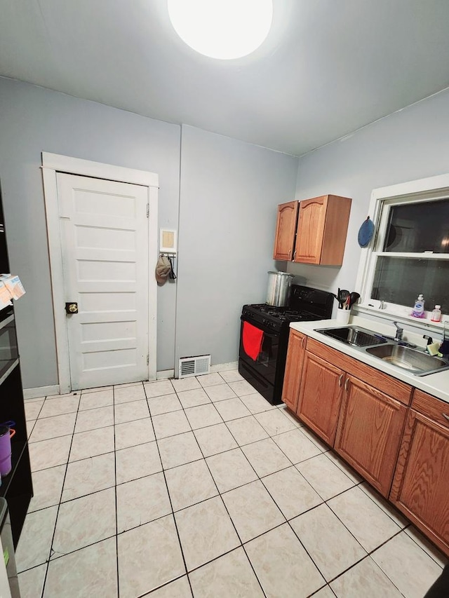 kitchen with gas stove, sink, and light tile patterned flooring