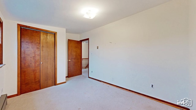 unfurnished bedroom featuring a closet and light colored carpet