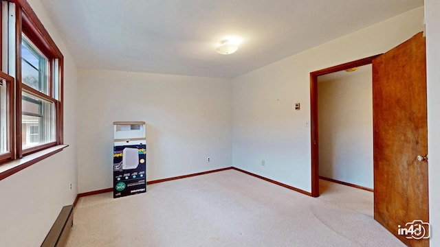 unfurnished room featuring light colored carpet and baseboard heating