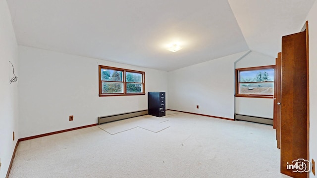 carpeted spare room with lofted ceiling and a baseboard heating unit