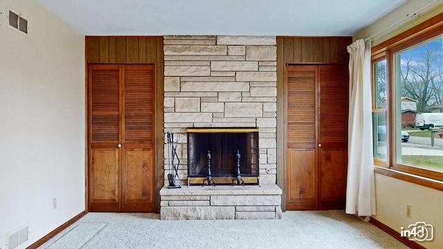 unfurnished living room featuring a stone fireplace and light colored carpet