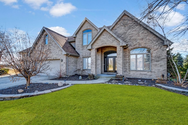 french country style house featuring a garage, a front lawn, and brick siding