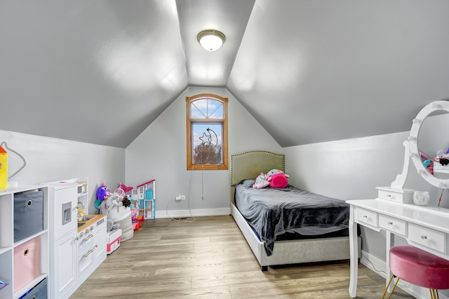 bedroom featuring lofted ceiling, light wood-type flooring, and baseboards