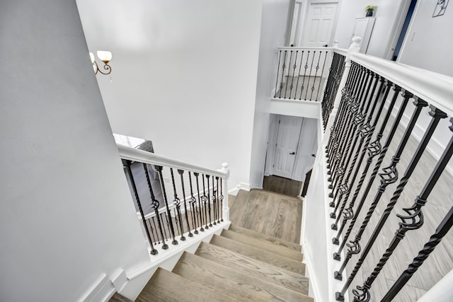 staircase with a high ceiling, baseboards, and wood finished floors