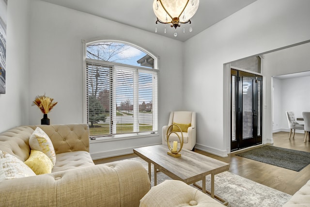 living room featuring a wealth of natural light, baseboards, a chandelier, and wood finished floors