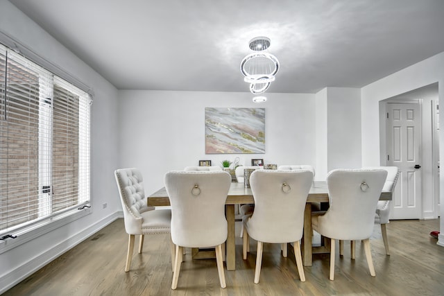 dining room featuring a notable chandelier, visible vents, baseboards, and wood finished floors