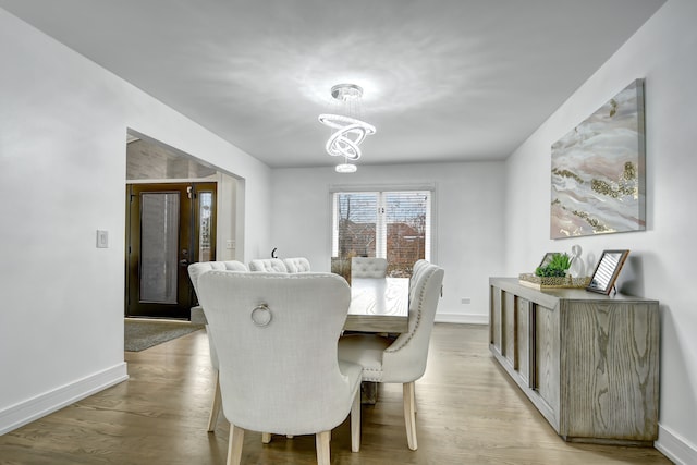 dining space featuring a notable chandelier, wood finished floors, and baseboards