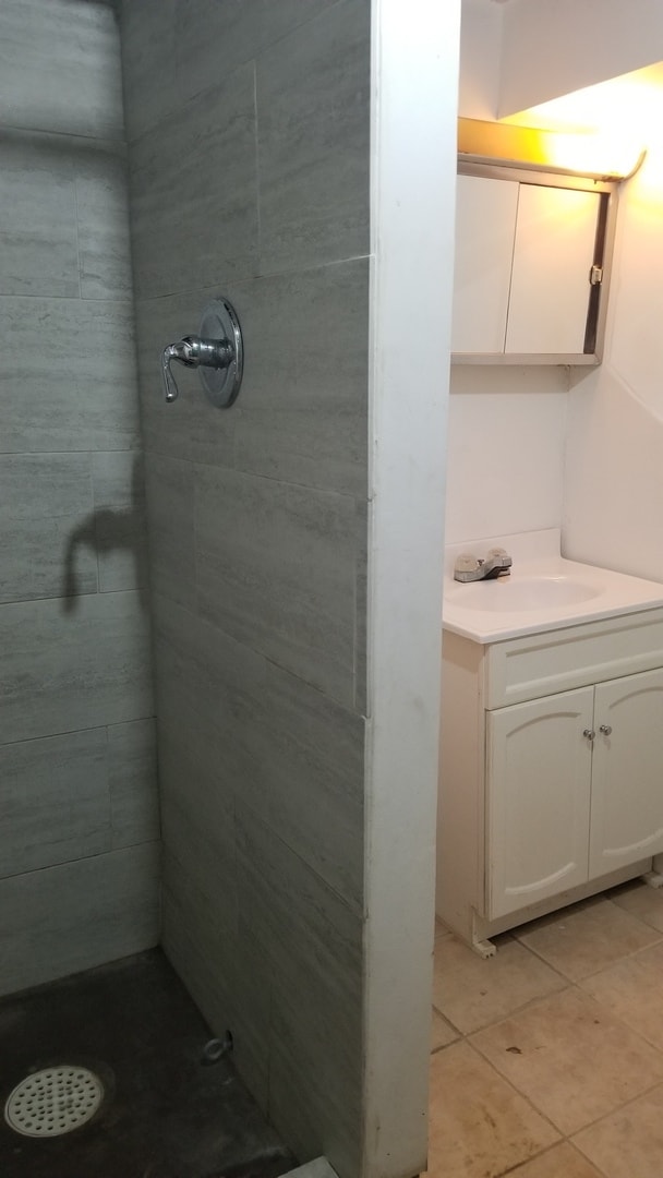 bathroom featuring tile patterned floors, vanity, and a tile shower