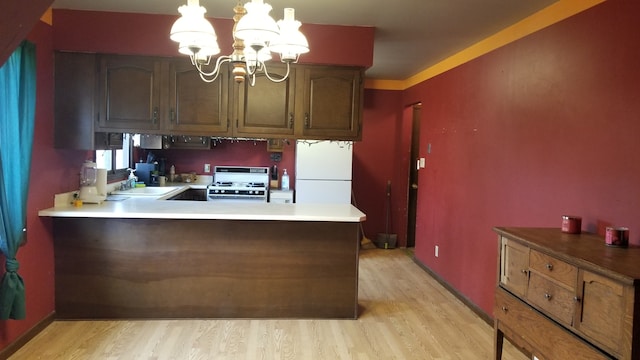 kitchen with kitchen peninsula, white appliances, decorative light fixtures, and light hardwood / wood-style floors