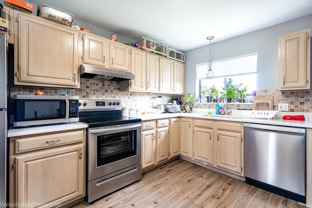 kitchen with sink, light brown cabinets, stainless steel appliances, light hardwood / wood-style floors, and decorative backsplash