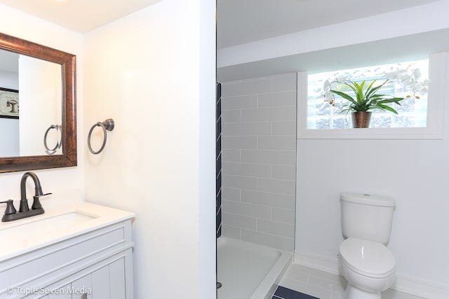 bathroom with tile patterned flooring, vanity, toilet, and a tile shower