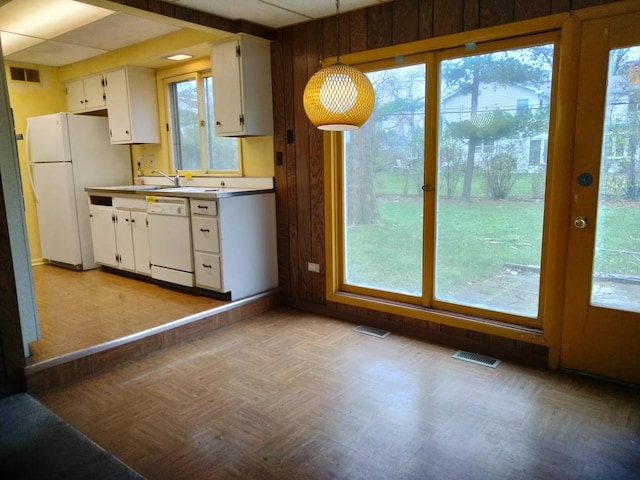 kitchen featuring pendant lighting, plenty of natural light, white cabinetry, and white appliances