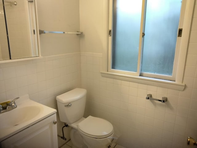 bathroom with vanity, tile walls, and toilet