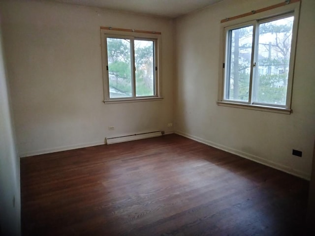 spare room with dark hardwood / wood-style flooring, a baseboard radiator, and a wealth of natural light