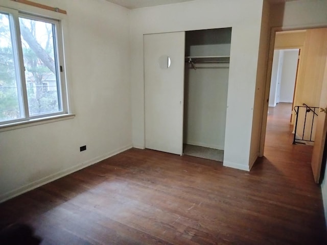 unfurnished bedroom with dark hardwood / wood-style floors and a closet