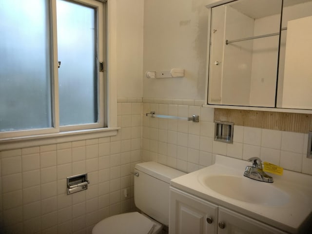 bathroom featuring vanity, toilet, and tile walls