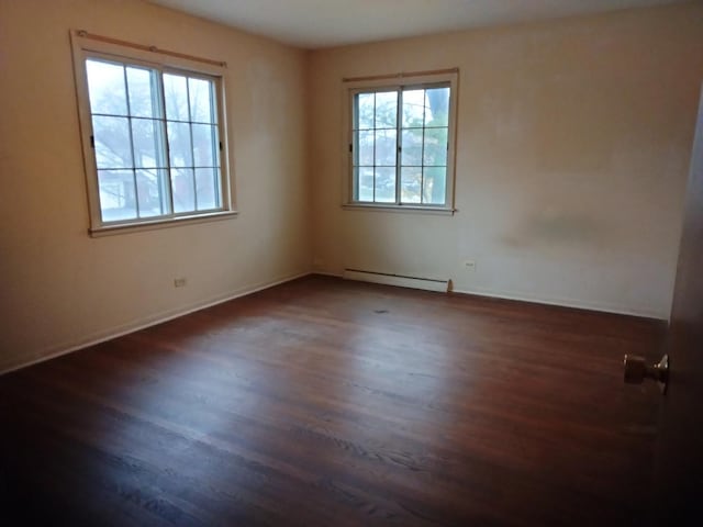 spare room featuring baseboard heating and dark wood-type flooring