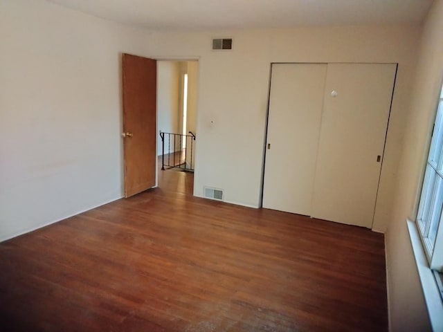 unfurnished bedroom featuring a closet and dark hardwood / wood-style floors