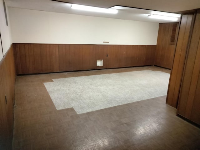 carpeted spare room featuring wooden walls