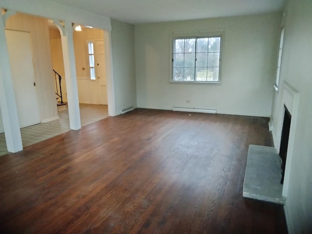 unfurnished living room featuring dark wood-type flooring and a baseboard heating unit