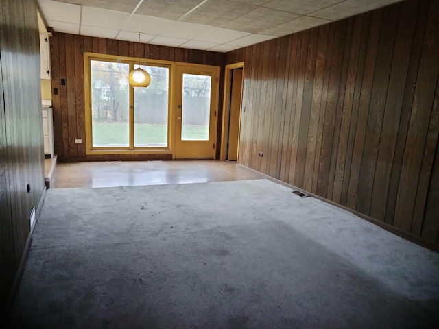 empty room featuring a paneled ceiling and wooden walls