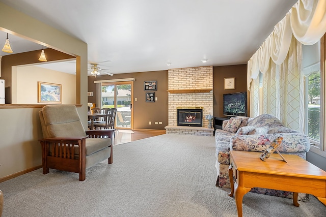 living room featuring a fireplace, ceiling fan, and carpet