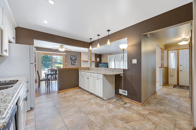 kitchen featuring ceiling fan, white cabinetry, hanging light fixtures, light stone counters, and kitchen peninsula