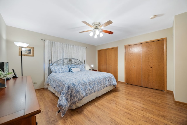 bedroom with light wood-type flooring, two closets, and ceiling fan