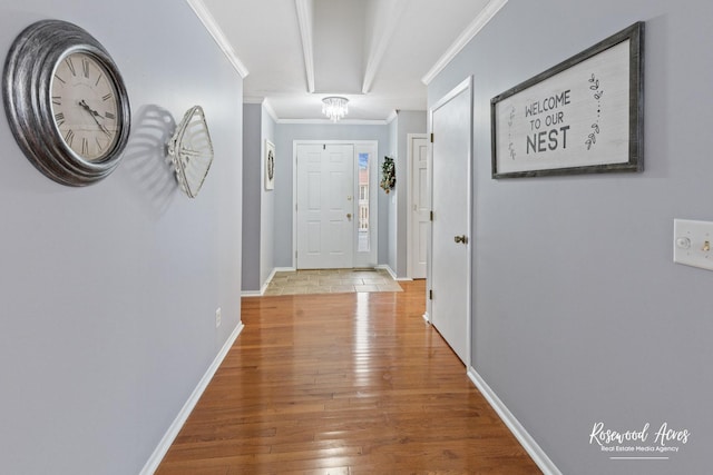 hallway with crown molding, hardwood / wood-style floors, and a notable chandelier