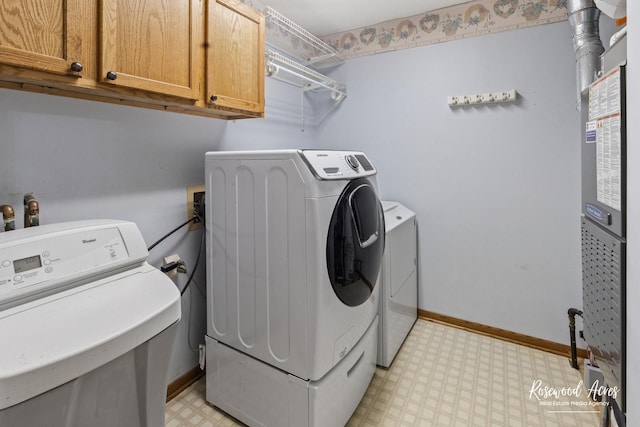 laundry area featuring washer and clothes dryer and cabinets