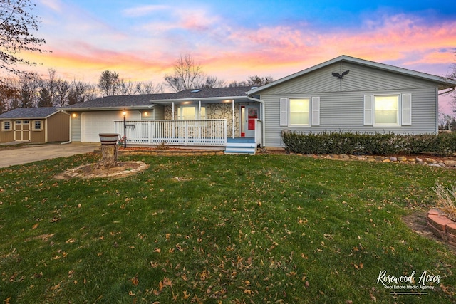 single story home featuring covered porch, a yard, an outbuilding, and a garage