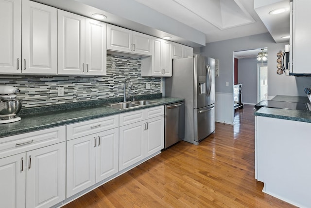 kitchen featuring appliances with stainless steel finishes, tasteful backsplash, sink, light hardwood / wood-style flooring, and white cabinets