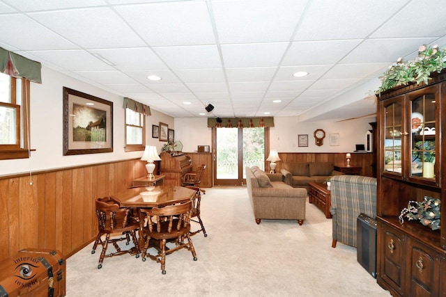 carpeted living room with a drop ceiling and wooden walls