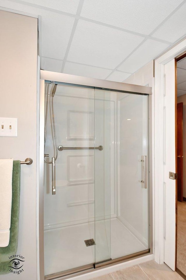 bathroom featuring a drop ceiling, a shower with shower door, and tile patterned floors