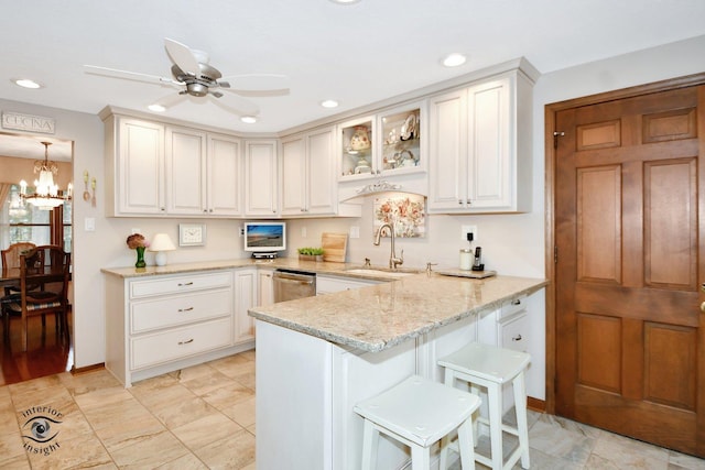 kitchen featuring pendant lighting, sink, light stone counters, white cabinets, and a kitchen bar