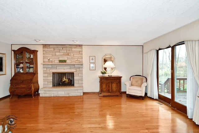 sitting room featuring a fireplace, a textured ceiling, and light wood-type flooring