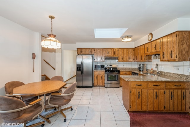 kitchen featuring backsplash, sink, appliances with stainless steel finishes, decorative light fixtures, and kitchen peninsula