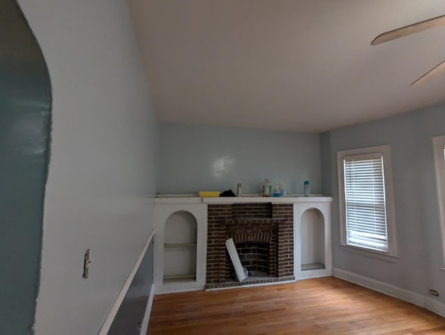 unfurnished living room with a fireplace, built in shelves, and light hardwood / wood-style flooring