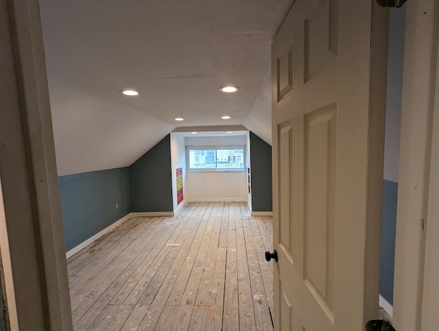 bonus room with light wood-type flooring and vaulted ceiling