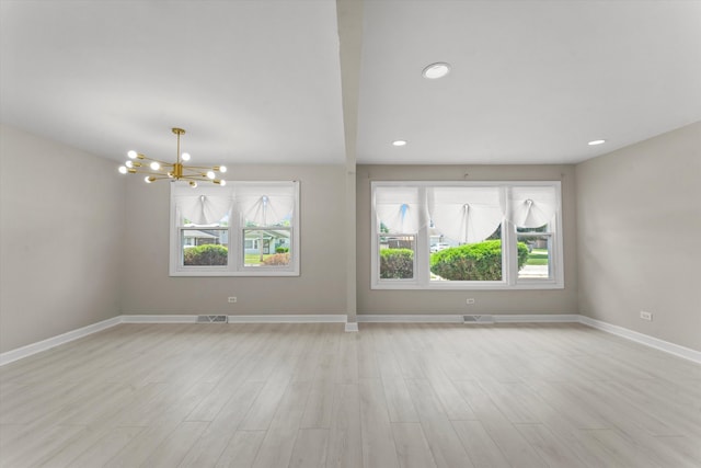 unfurnished room featuring a chandelier and light hardwood / wood-style floors