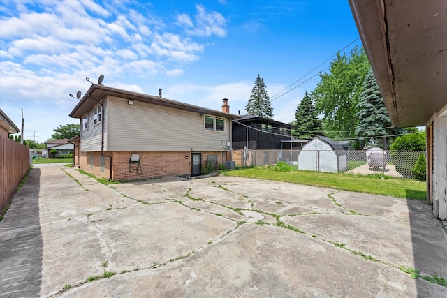 back of property featuring a yard, a patio, and a storage shed