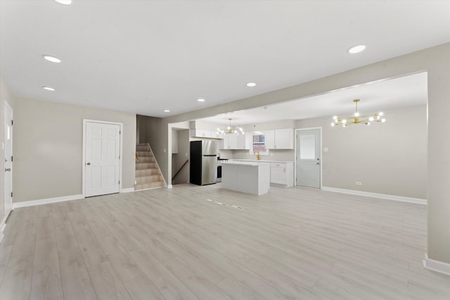 unfurnished living room with a chandelier and light wood-type flooring