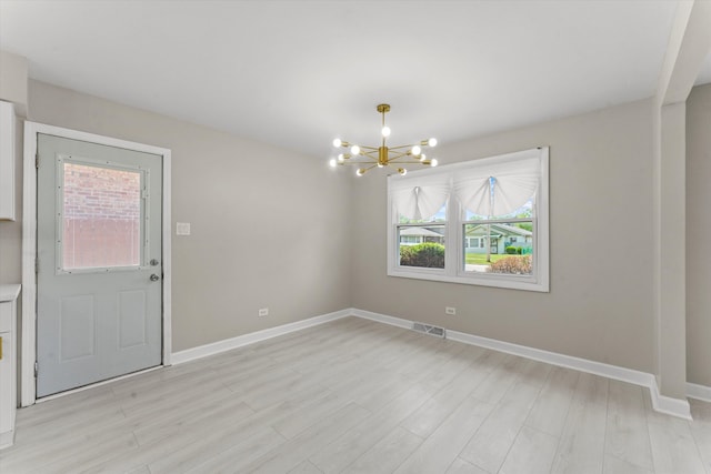 unfurnished dining area with light hardwood / wood-style floors and an inviting chandelier