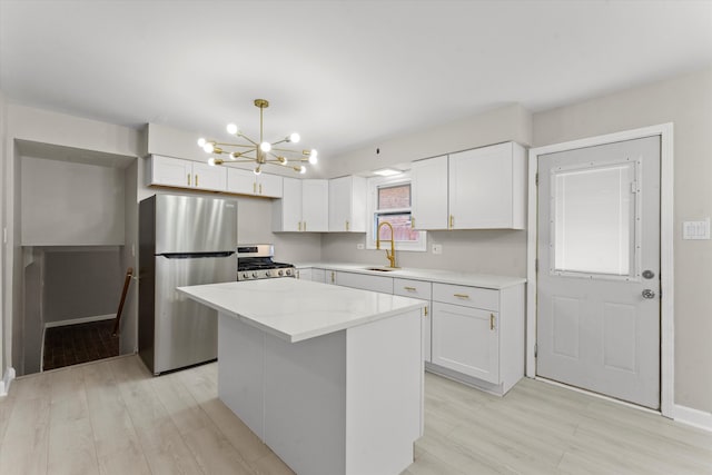 kitchen featuring white cabinets, appliances with stainless steel finishes, a kitchen island, and sink