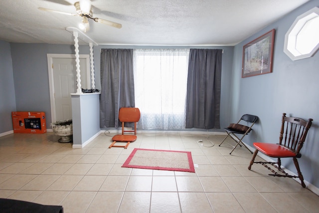 living area with ceiling fan, light tile patterned flooring, and a textured ceiling