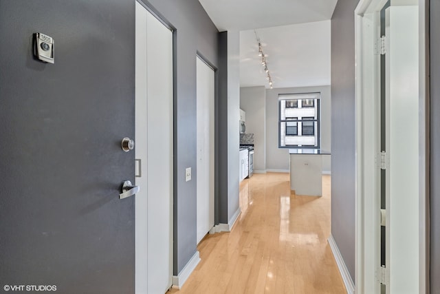 hallway featuring light hardwood / wood-style flooring and track lighting