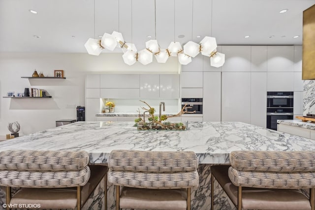 kitchen featuring light stone counters, decorative light fixtures, modern cabinets, and white cabinets