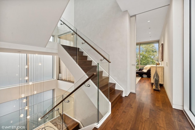 stairs with floor to ceiling windows, baseboards, and wood finished floors