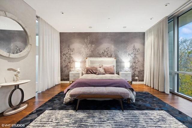 bedroom with access to outside, floor to ceiling windows, wallpapered walls, and wood finished floors